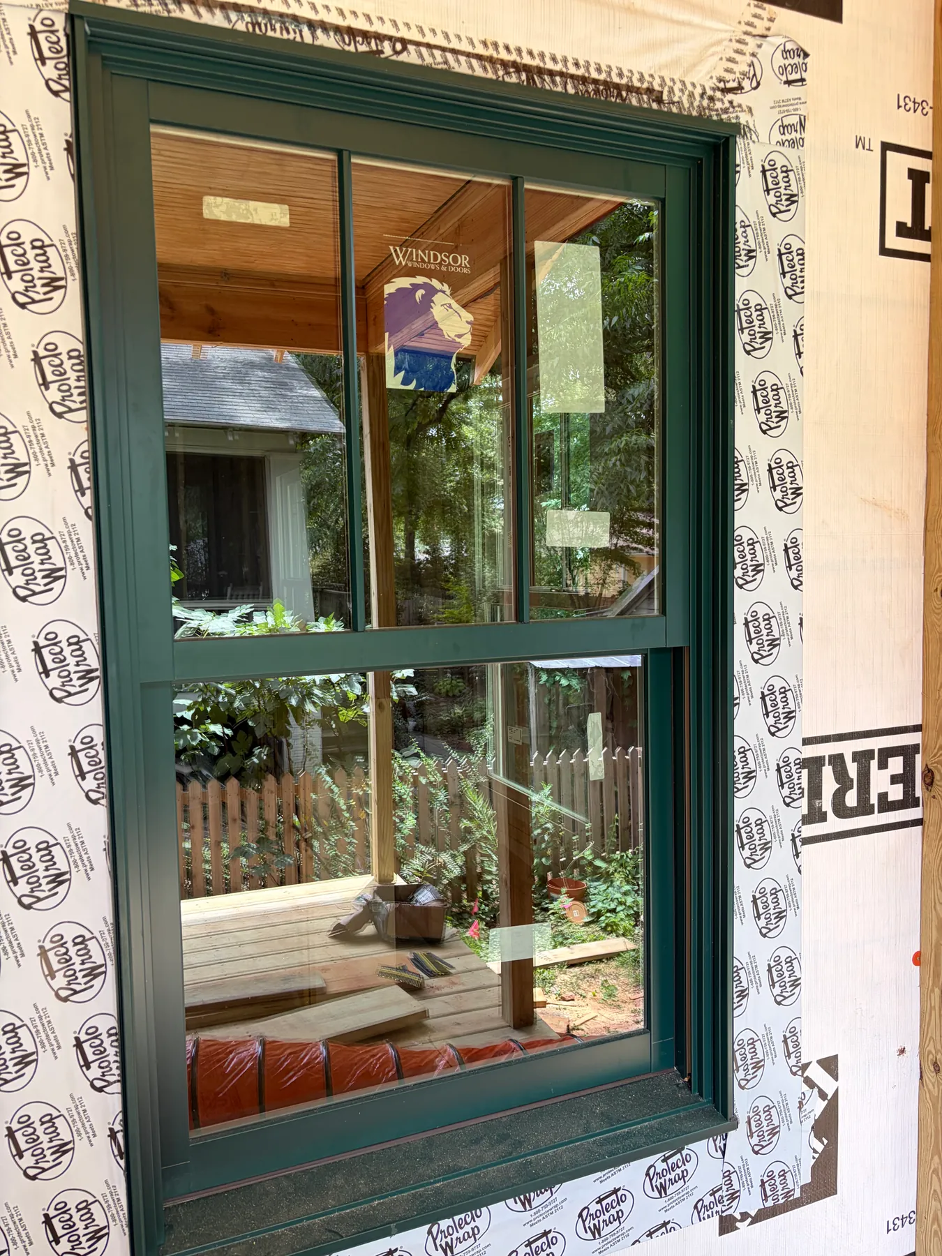 Close view of a newly installed dark green window within exposed exterior weather barrier on the Janet addition