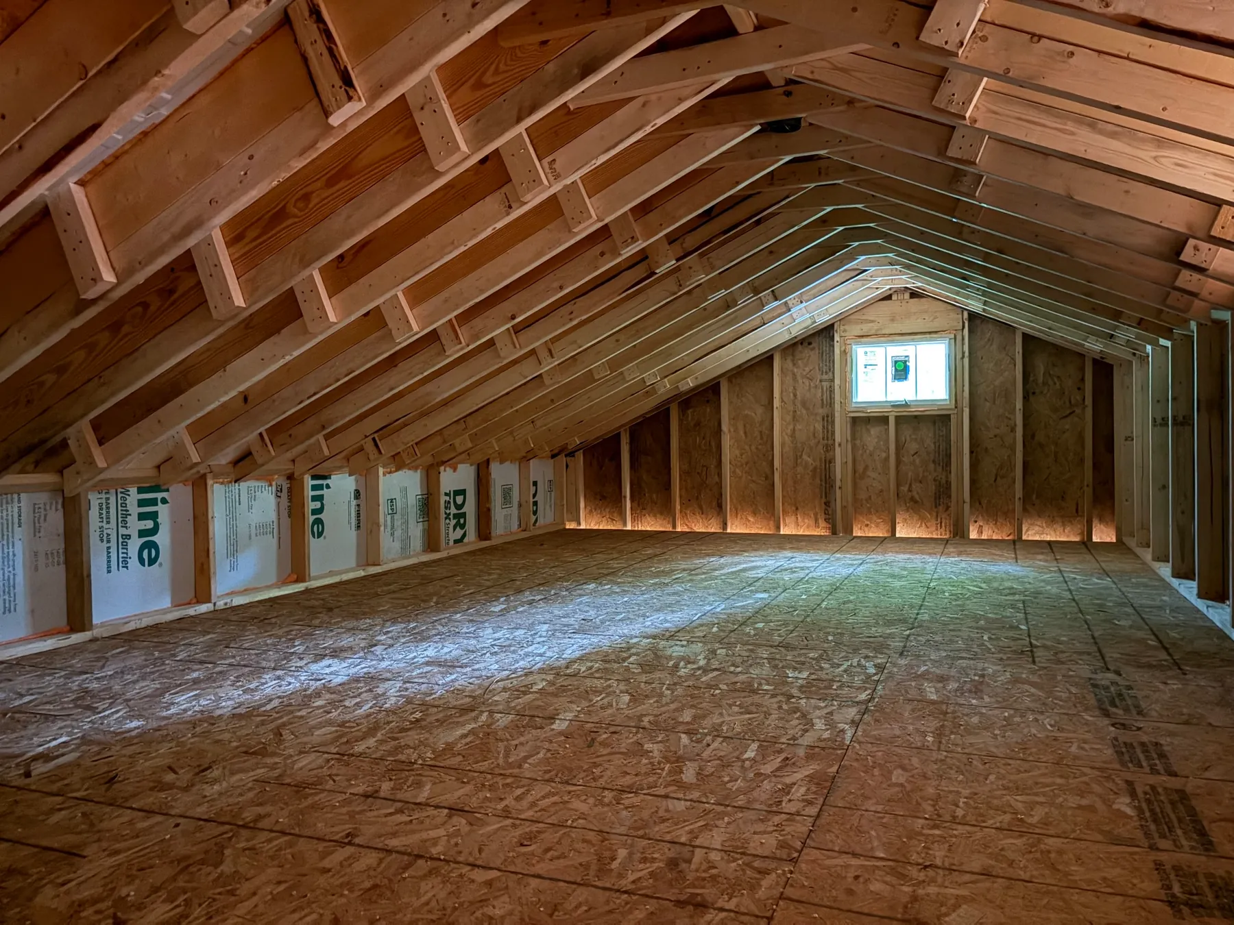 Interior view of exposed roof rafters, wall framing, and subfloor in the Janet home addition