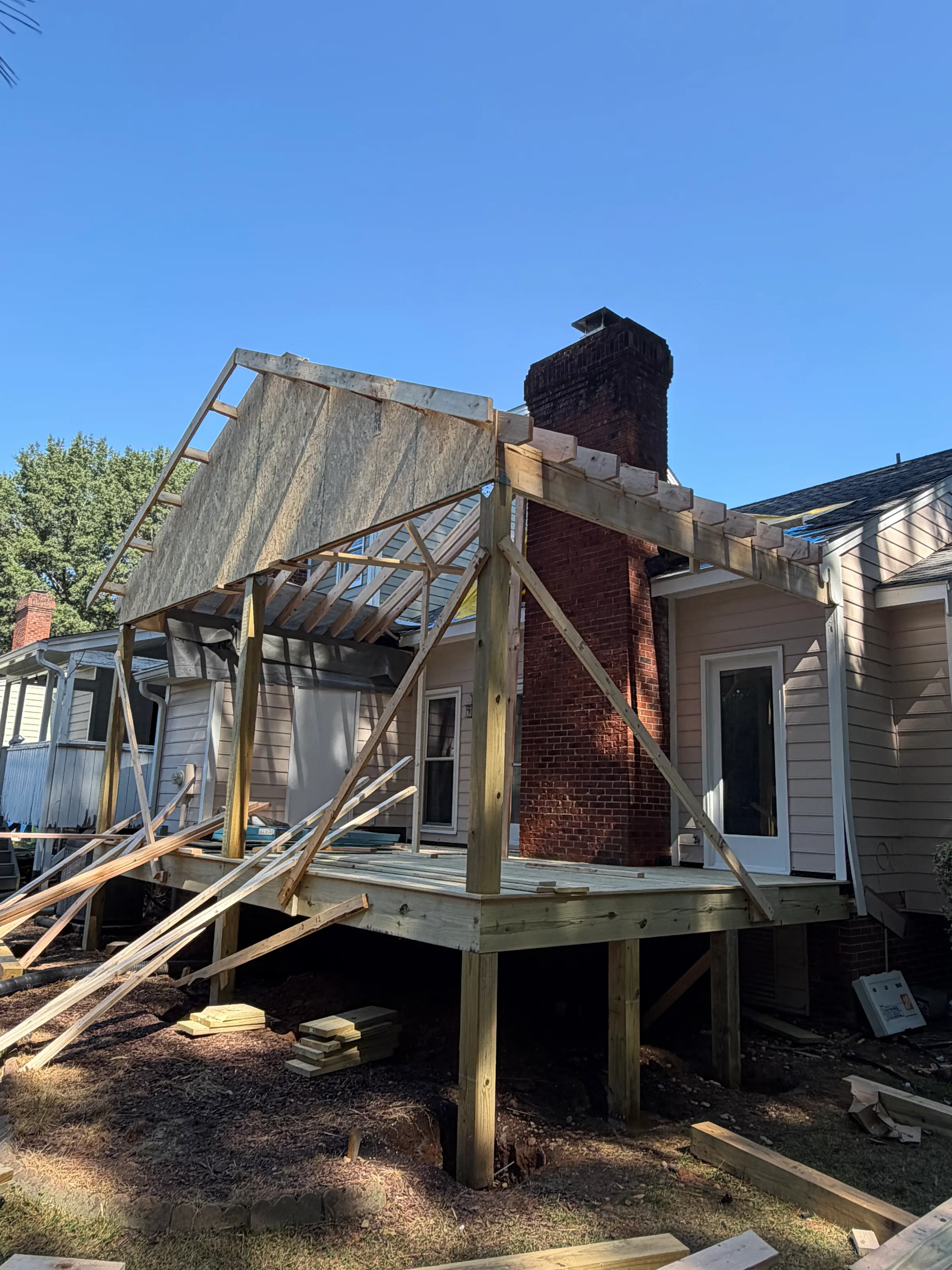 Closer construction view of the Mazingo covered porch posts, floor framing, roof rafters, gable sheathing, and townhouse connection